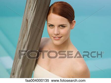 Woman leaning against wooden pole, swimming pool in background View Large Photo Image Stock Photography - Woman leaning against wooden pole, swimming pool in background. Fotosearch