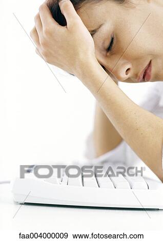 Woman leaning over keyboard holding head View Large Photo Image Stock Photo - Woman leaning over keyboard holding head. Fotosearch