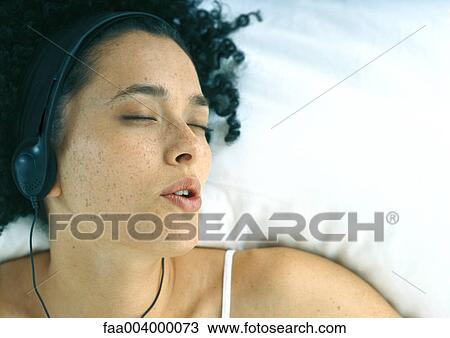 Woman listening to headphones in bed View Large Photo Image Stock Image - Woman listening to headphones in bed. Fotosearch