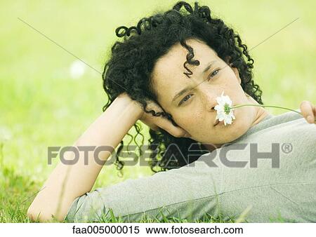 Woman lying on ground and holding daisy to nose View Large Photo Image Stock Photography - Woman lying on ground and holding daisy to nose. Fotosearch