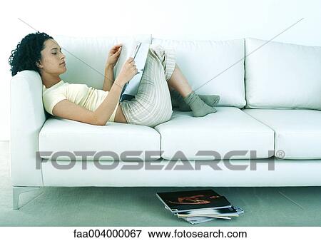 Woman lying on sofa looking at magazines View Large Photo Image Stock Photo - Woman lying on sofa looking at magazines. Fotosearch