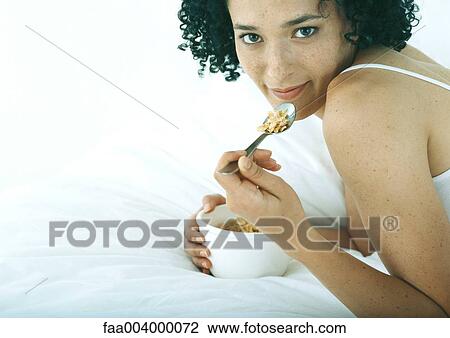 Woman lying on stomach in bed, eating cereal View Large Photo Image Stock Image - Woman lying on stomach in bed, eating cereal. Fotosearch