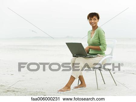 Woman on beach, sitting in chair using laptop View Large Photo Image Stock Image - Woman on beach, sitting in chair using laptop. Fotosearch