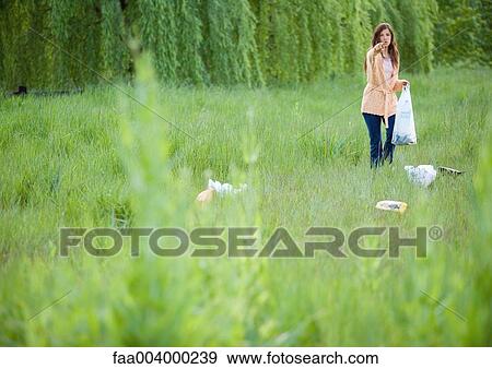 Woman picking up litter in field, pointing at camera View Large Photo Image Stock Photo - Woman picking up litter in field, pointing at camera. Fotosearch