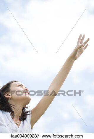Woman reaching toward sky, low angle view View Large Photo Image Stock Photo - Woman reaching toward sky, low angle view. Fotosearch