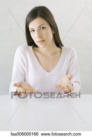 Woman sitting at table gesturing, looking at camera View Large Photo Image Stock Photograph - Woman sitting at table gesturing, looking at camera. Fotosearch
