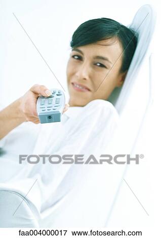 Woman sitting back, smiling, and pointing remote control at camera View Large Photo Image Stock Photo - Woman sitting back, smiling, and pointing remote control at camera. Fotosearch