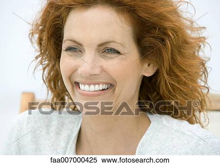 Stock Photography - Woman sitting in beach chair, smiling. Fotosearch
