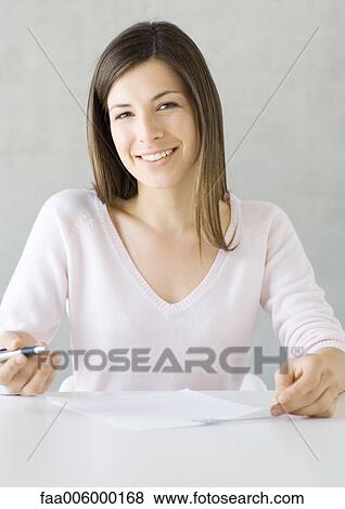 Stock Photo - Woman sitting with pen and document. Fotosearch