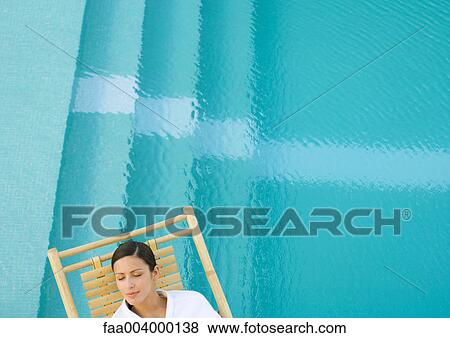 Stock Photo - Woman sleeping in lounge chair next to pool. Fotosearch