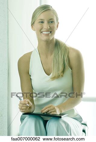 Woman smiling with file on lap View Large Photo Image Stock Image - Woman smiling with file on lap. Fotosearch