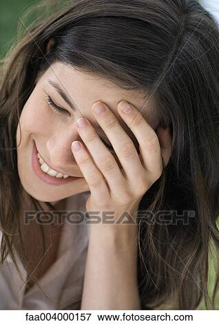 Stock Photo - Woman smiling with hand over eye. Fotosearch