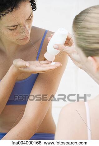 Woman squeezing sunscreen into friend's hand View Large Photo Image Stock Photograph - Woman squeezing sunscreen into friend's hand. Fotosearch