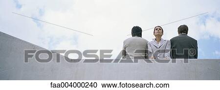 Woman standing between two men with backs turned View Large Photo Image Stock Image - Woman standing between two men with backs turned. Fotosearch