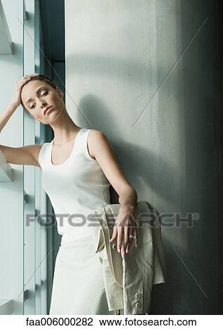 Woman standing near window, holding head View Large Photo Image Stock Image - Woman standing near window, holding head. Fotosearch