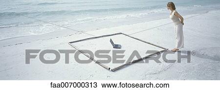 Woman standing on beach looking at laptop inside of sqaure View Large Photo Image Stock Image - Woman standing on beach looking at laptop inside of sqaure. Fotosearch