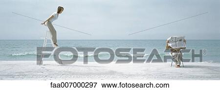 Woman standing on ladder on beach, man reading newspaper View Large Photo Image Stock Photo - Woman standing on ladder on beach, man reading newspaper. Fotosearch