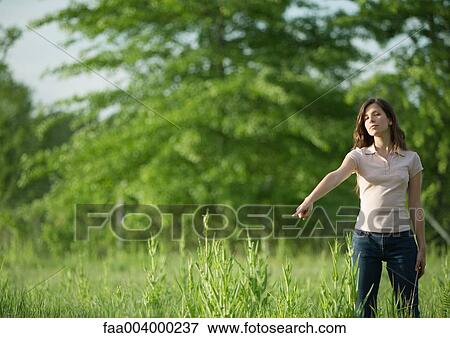 Woman standing outdoors pointing toward ground View Large Photo Image Stock Photo - Woman standing outdoors pointing toward ground. Fotosearch