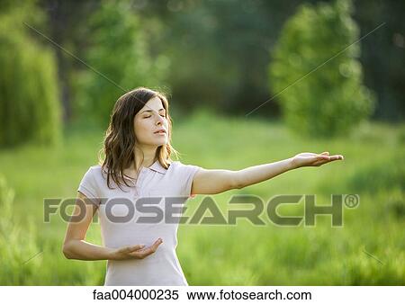 Woman standing outdoors with arm outstretched and eyes closed View Large Photo Image Stock Photography - Woman standing outdoors with arm outstretched and eyes closed. Fotosearch