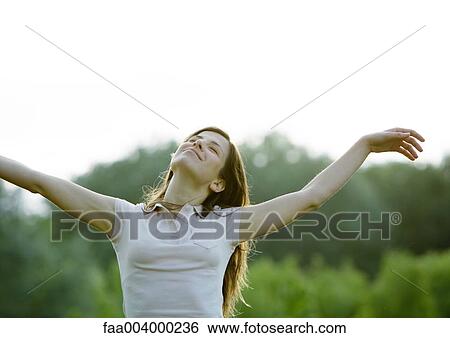 Woman standing outdoors with eyes closed and arms up View Large Photo Image Stock Photograph - Woman standing outdoors with eyes closed and arms up . Fotosearch