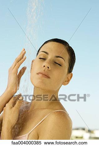 Stock Photography - Woman standing under outdoor shower. Fotosearch