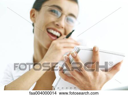Picture - Woman talking on phone and holding notepad. Fotosearch