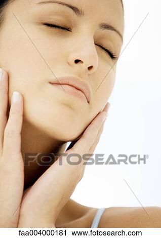 Stock Image - Woman touching face with eyes closed. Fotosearch