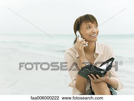 Woman using cell phone and holding agenda, sea in background View Large Photo Image Stock Image - Woman using cell phone and holding agenda, sea in background. Fotosearch