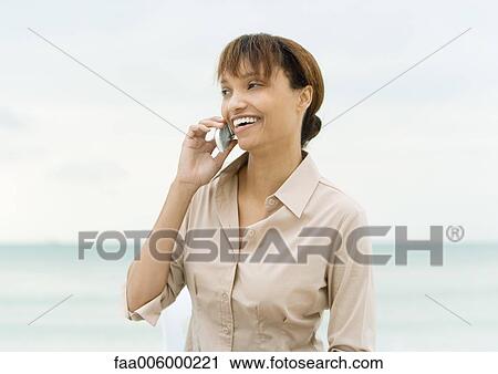 Woman using cell phone, sea in background View Large Photo Image Stock Image - Woman using cell phone, sea in background. Fotosearch