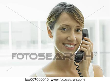 Woman using landline phone, smiling at camera View Large Photo Image Stock Image - Woman using landline phone, smiling at camera. Fotosearch