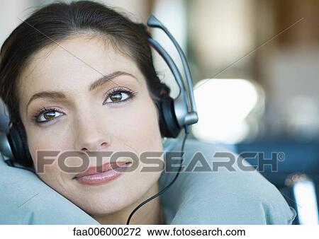 Woman wearing headphones and using neck pillow View Large Photo Image Stock Image - Woman wearing headphones and using neck pillow. Fotosearch