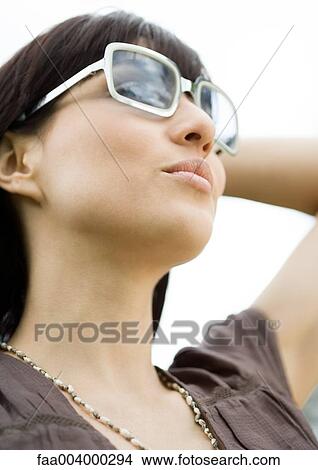 Picture - Woman wearing sunglasses, low angle view. Fotosearch