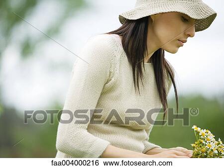 Woman wearing sunhat, holding bunch of flowers View Large Photo Image Stock Photograph - Woman wearing sunhat, holding bunch of flowers. Fotosearch