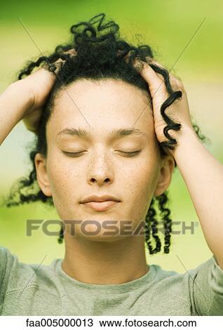 Stock Image - Woman with eyes closed and hands in hair. Fotosearch