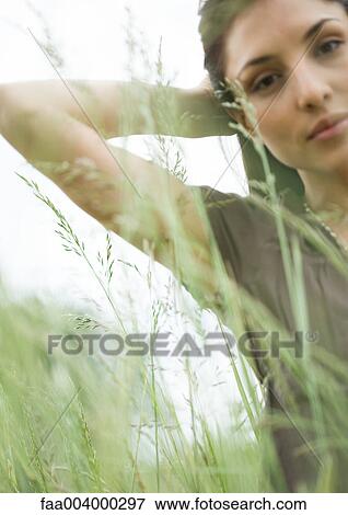 Woman with hand behind head, seen through long grass View Large Photo Image Stock Photo - Woman with hand behind head, seen through long grass. Fotosearch