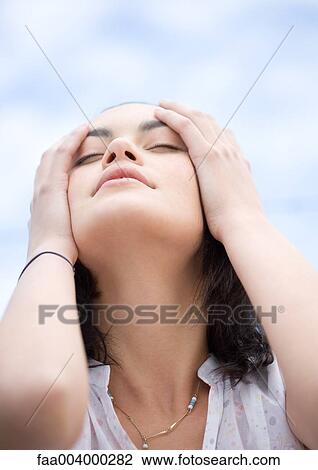 Woman with hands on side of head, low angle view with sky in background View Large Photo Image Stock Image - Woman with hands on side of head, low angle view with sky in background. Fotosearch