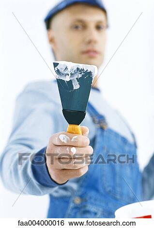 Worker holding out putty knife View Large Photo Image Stock Photograph - Worker holding out putty knife. Fotosearch