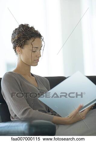 Stock Photography - Young businesswoman sitting and looking at file. Fotosearch
