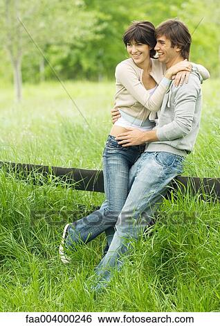Young couple embracing and leaning against fence View Large Photo Image Stock Photograph - Young couple embracing and leaning against fence. Fotosearch