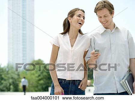 Stock Image - Young couple in urban setting, man checking cell phone. Fotosearch