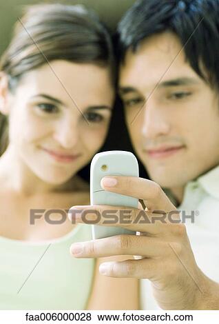 Young couple looking at messaging phone View Large Photo Image Stock Photo - Young couple looking at messaging phone. Fotosearch