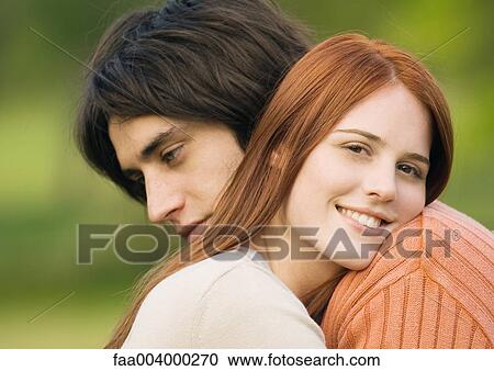 Stock Image - Young couple resting heads on each other's shoulders. Fotosearch