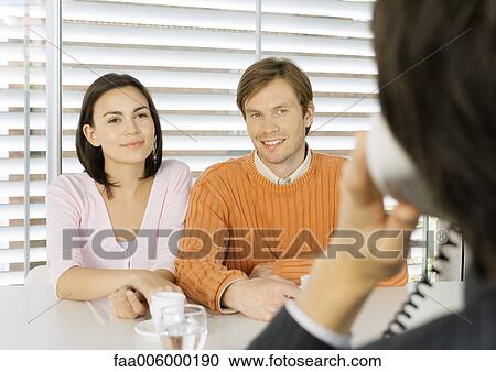 Young couple sitting across from salesman View Large Photo Image Stock Image - Young couple sitting across from salesman. Fotosearch