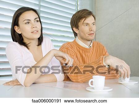 Young couple sitting at table with cups of coffee View Large Photo Image Stock Image - Young couple sitting at table with cups of coffee. Fotosearch