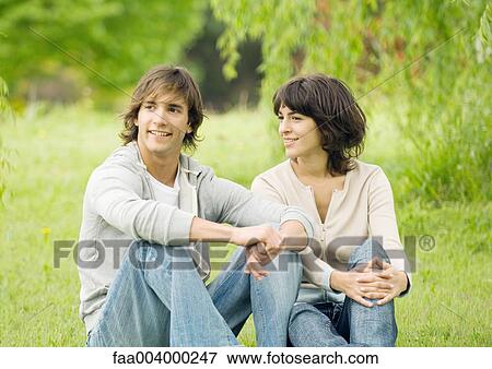 Young couple sitting on grass View Large Photo Image Stock Photo - Young couple sitting on grass. Fotosearch