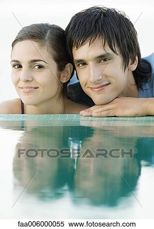 Stock Photography - Young couple with heads by edge of water, close-up. Fotosearch