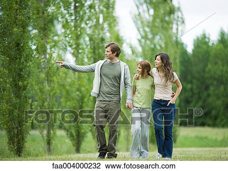 Stock Image - Young family going for walk, man pointing. Fotosearch
