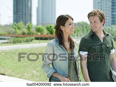 Young man and woman walking in city park View Large Photo Image Stock Image - Young man and woman walking in city park. Fotosearch
