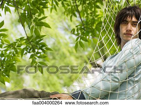 Picture - Young man in hammock, looking at camera. Fotosearch