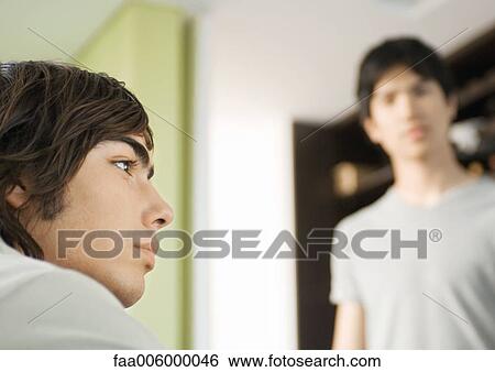 Young man looking away, friend in background View Large Photo Image Stock Photograph - Young man looking away, friend in background. Fotosearch